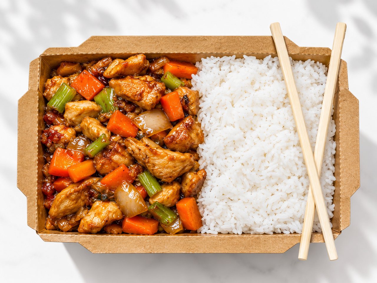 Chicken and vegetables served with white rice in a takeaway box.