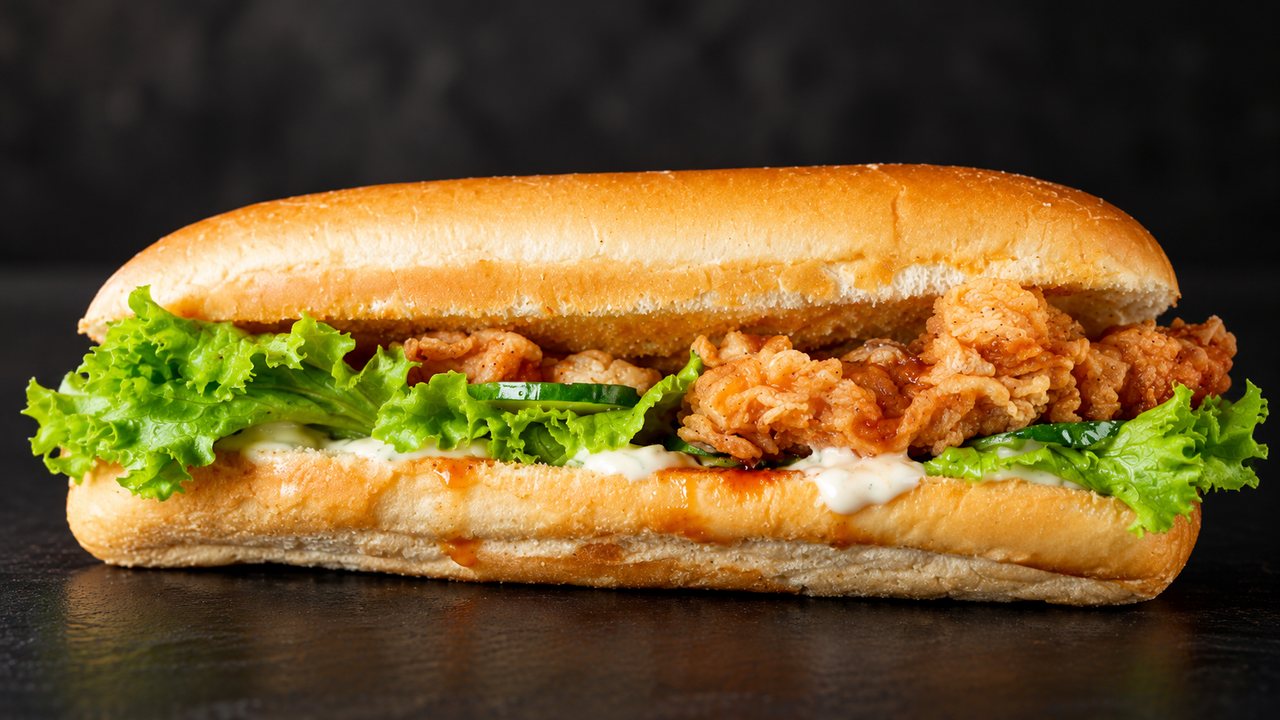 A crispy chicken sub with lettuce and cucumber in a toasted roll.