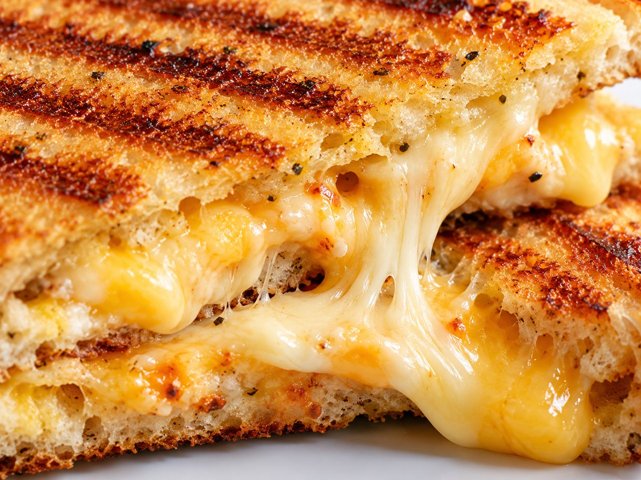 A close view of a golden grilled-cheese sandwich with melted filling.